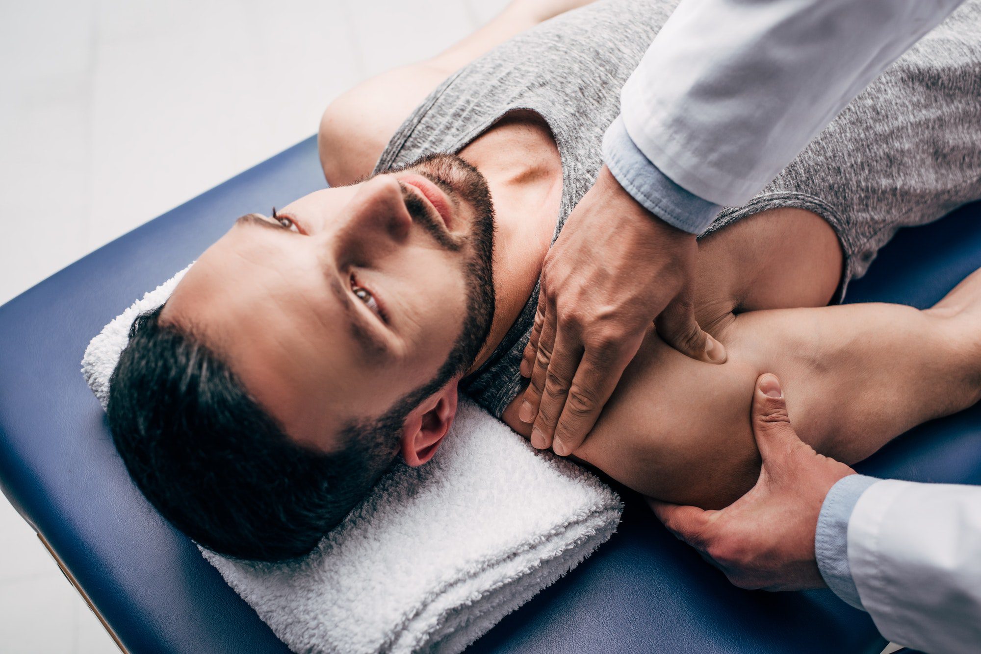 chiropractor massaging shoulder of man on Massage Table in hospital