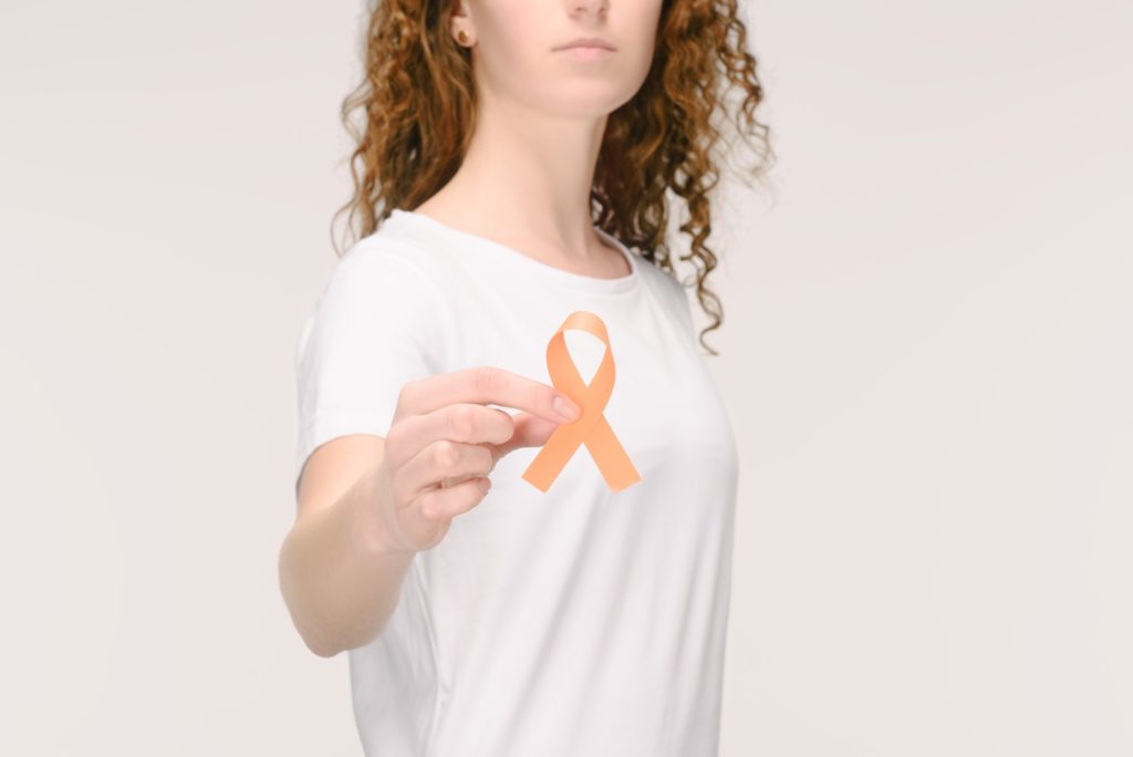 cropped shot of woman showing leukemia, kidney cancer, multiple sclerosis RSD awareness ribbon in